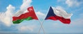 two crossed flags Czech Republic and Oman waving in wind at cloudy sky. Concept of relationship, dialog, travelling between two