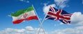 two crossed flags Great Britain and Iran waving in wind at cloudy sky. Concept of relationship, dialog, travelling between two