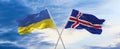 two crossed flags Iceland and Ukraine waving in wind at cloudy sky. Concept of relationship, dialog, travelling between two