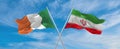 two crossed flags Iran and Ireland waving in wind at cloudy sky. Concept of relationship, dialog, travelling between two countries