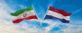 two crossed flags Iran and Netherland waving in wind at cloudy sky. Concept of relationship, dialog, travelling between two