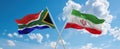 two crossed flags Iran and South Africa waving in wind at cloudy sky. Concept of relationship, dialog, travelling between two