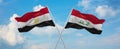 two crossed flags Iraq and Egypt waving in wind at cloudy sky. Concept of relationship, dialog, travelling between two countries