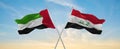 two crossed flags Iraq and United Arab Emirates waving in wind at cloudy sky. Concept of relationship, dialog, travelling between