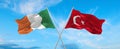 two crossed flags Ireland and Turkey waving in wind at cloudy sky. Concept of relationship, dialog, travelling between two