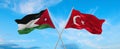 two crossed flags Jordan and Turkey waving in wind at cloudy sky. Concept of relationship, dialog, travelling between two
