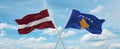 two crossed flags Kosovo and Latvia waving in wind at cloudy sky. Concept of relationship, dialog, travelling between two