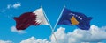 two crossed flags Kosovo and Qatar waving in wind at cloudy sky. Concept of relationship, dialog, travelling between two countries