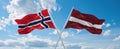 two crossed flags latvia and Norway waving in wind at cloudy sky. Concept of relationship, dialog, travelling between two