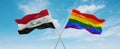 two crossed flags LGBT Pride and Iraq waving in wind at cloudy sky. Concept of relationship, dialog, travelling between two