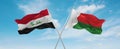 two crossed flags Madagascar and Iraq waving in wind at cloudy sky. Concept of relationship, dialog, travelling between two
