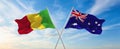 two crossed flags Mali and Australia waving in wind at cloudy sky. Concept of relationship, dialog, travelling between two Royalty Free Stock Photo