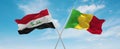 two crossed flags Mali and Iraq waving in wind at cloudy sky. Concept of relationship, dialog, travelling between two countries