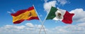 two crossed flags Mexico and spain waving in wind at cloudy sky. Concept of relationship, dialog, travelling between two countries