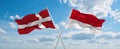 two crossed flags Monaco and Denmark waving in wind at cloudy sky. Concept of relationship, dialog, travelling between two