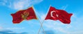 two crossed flags Montenegro and Turkey waving in wind at cloudy sky. Concept of relationship, dialog, travelling between two