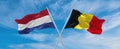 two crossed flags netherlands and Belgium waving in wind at cloudy sky. Concept of relationship, dialog, travelling between two