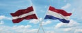 two crossed flags netherlands and Latvia waving in wind at cloudy sky. Concept of relationship, dialog, travelling between two