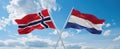 two crossed flags netherlands and Norway waving in wind at cloudy sky. Concept of relationship, dialog, travelling between two