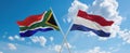 two crossed flags netherlands and South Africa waving in wind at cloudy sky. Concept of relationship, dialog, travelling between