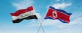 two crossed flags North Korea and Iraq waving in wind at cloudy sky. Concept of relationship, dialog, travelling between two