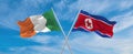 two crossed flags North Korea and Ireland waving in wind at cloudy sky. Concept of relationship, dialog, travelling between two