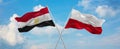 two crossed flags poland and Egypt waving in wind at cloudy sky. Concept of relationship, dialog, travelling between two countries