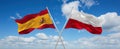 two crossed flags poland and spain waving in wind at cloudy sky. Concept of relationship, dialog, travelling between two countries