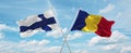 two crossed flags romania and finland waving in wind at cloudy sky. Concept of relationship, dialog, travelling between two