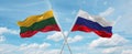 two crossed flags Russia and Lithuania waving in wind at cloudy sky. Concept of relationship, dialog, travelling between two