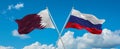 two crossed flags Russia and Qatar waving in wind at cloudy sky. Concept of relationship, dialog, travelling between two countries