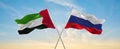 two crossed flags Russia and United Arab Emirates waving in wind at cloudy sky. Concept of relationship, dialog, travelling Royalty Free Stock Photo