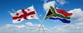 two crossed flags South Africa and Georgia waving in wind at cloudy sky. Concept of relationship, dialog, travelling between two