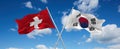 two crossed flags south korea and Switzerland waving in wind at cloudy sky. Concept of relationship, dialog, travelling between