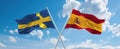 two crossed flags Spain and Sweden waving in wind at cloudy sky. Concept of relationship, dialog, travelling between two countries