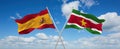 two crossed flags Suriname and spain waving in wind at cloudy sky. Concept of relationship, dialog, travelling between two