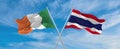 two crossed flags thailand and Ireland waving in wind at cloudy sky. Concept of relationship, dialog, travelling between two