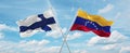 two crossed flags Venezuela and finland waving in wind at cloudy sky. Concept of relationship, dialog, travelling between two