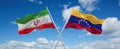 two crossed flags Venezuela and Iran waving in wind at cloudy sky. Concept of relationship, dialog, travelling between two