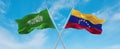 two crossed flags Venezuela and Saudi Arabia waving in wind at cloudy sky. Concept of relationship, dialog, travelling between two