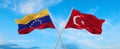 two crossed flags Venezuela and Turkey waving in wind at cloudy sky. Concept of relationship, dialog, travelling between two