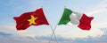 two crossed flags Vietnam and Italy waving in wind at cloudy sky. Concept of relationship, dialog, travelling between two