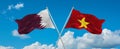 two crossed flags Vietnam and Qatar waving in wind at cloudy sky. Concept of relationship, dialog, travelling between two