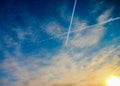 Two crossing airplane traces in bright blue sky during the dawn Royalty Free Stock Photo