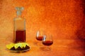 Two crystal glasses and a bottle of cognac, next to a plate with lemon slices and chocolates Royalty Free Stock Photo