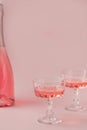 Two crystal glasses and bottle of rose sparkling wine or champagne on pastel pink background. Creative composition with Royalty Free Stock Photo