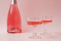 Two crystal glasses and bottle of rose sparkling wine or champagne on pastel pink background. Creative composition with Royalty Free Stock Photo