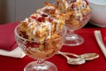 Two crystal goblets filled with Italian Panettone cranberry bread pudding with sauceboat in background