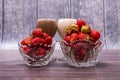Three crystal vases with ripe red strawberries and two glasses of cocktails stand on wooden table. Royalty Free Stock Photo