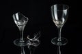 Two crystal wine glass and shattered glass on a black mirror background. Royalty Free Stock Photo